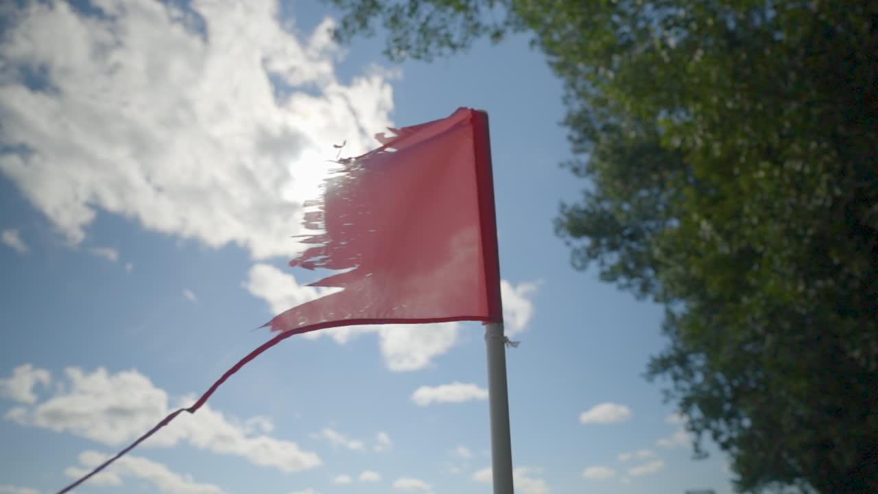 bandera roja vieja, rota y andrajosa que fluye en el viento en un día soleado