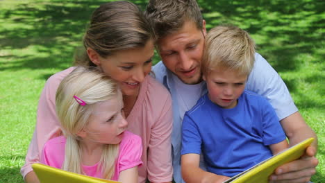 a family talking to each other while reading a book before looking at the camera and smiling