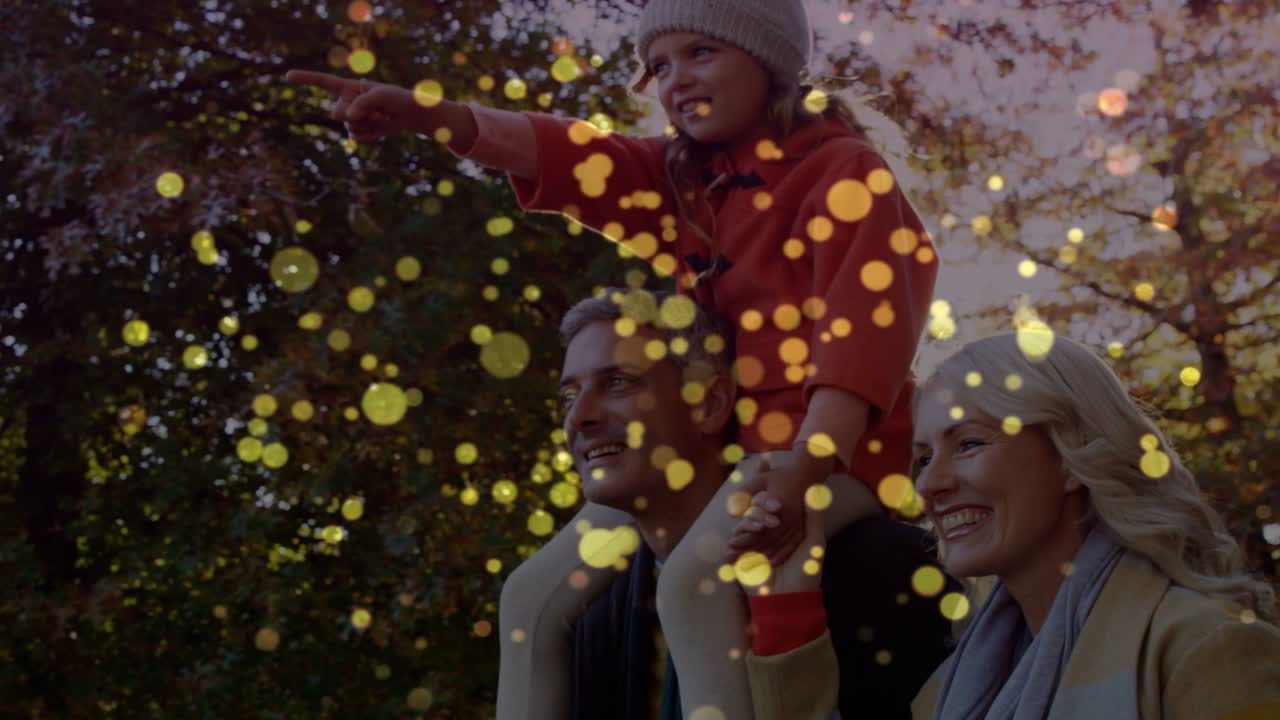 Famiglia che cammina, l'uomo tiene in braccio la bambina e indica, gli adulti seguono annunci pubblicitari con bokeh dorato fluttuante.