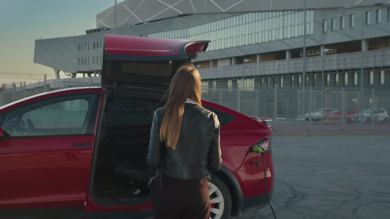 женщина заряжает электромобиль