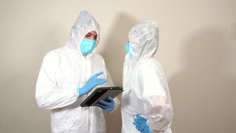 doctor in ppe with tablet calls coworker to show her information