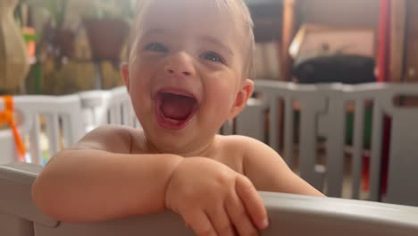 true laughter baby enjoying himself fun charismatic caucasian toddler in a playpen