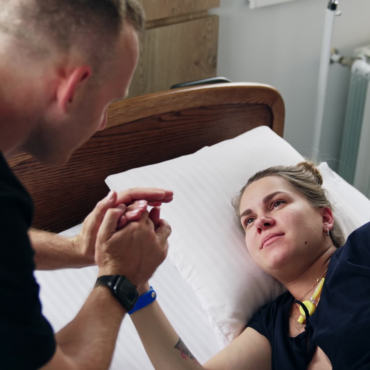 Expecting couple in the hospital ward. Man comforting his wife lying in bed and suffering from contractions