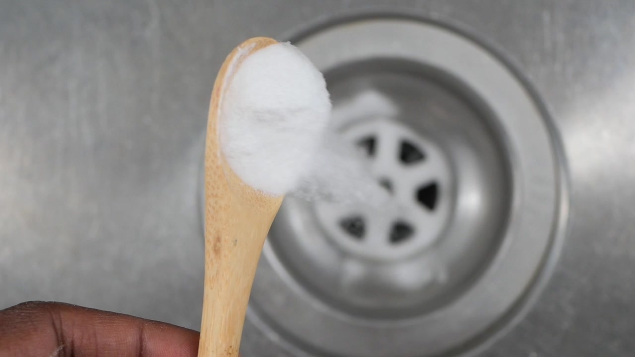 Pouring White Powder into a Kitchen Sink Drain