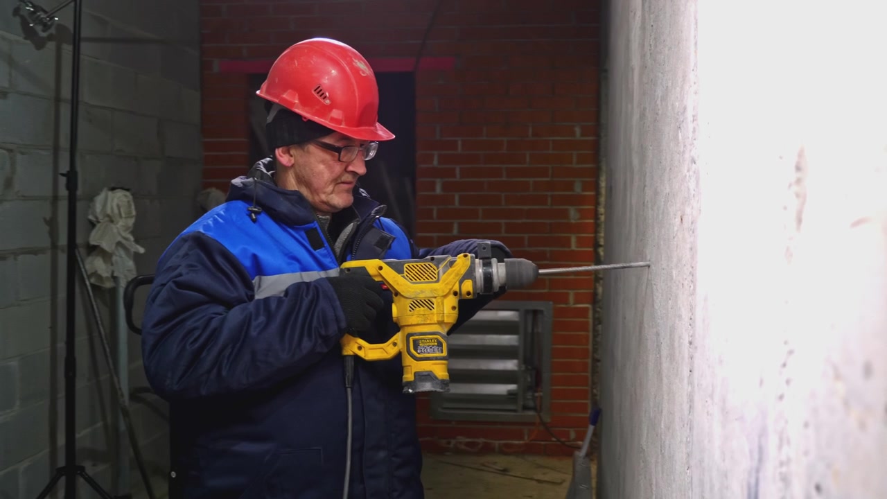 Construction worker drilling a hole in a concrete wall