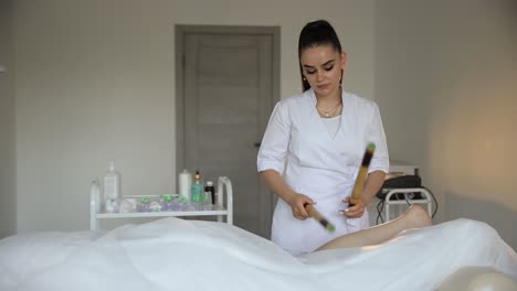woman receiving a leg massage with bamboo stick in a spa setting