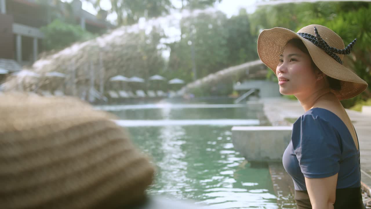 아시아 여성 여행자는 캐주얼 옷 드레스를 입고 휴가를 즐기고 해가 지는 순간을 즐기고 아시아 여성은 주말 여행을 즐기며 수영장 일몰 시간을 즐기고 있습니다.