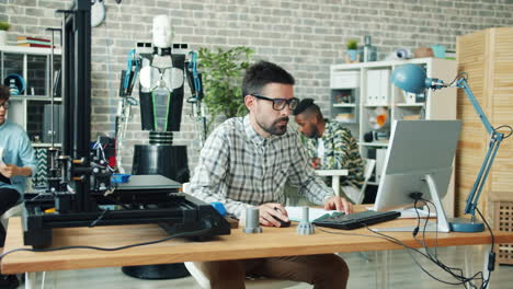 Team working in a modern tech office with a 3D printer and a robot