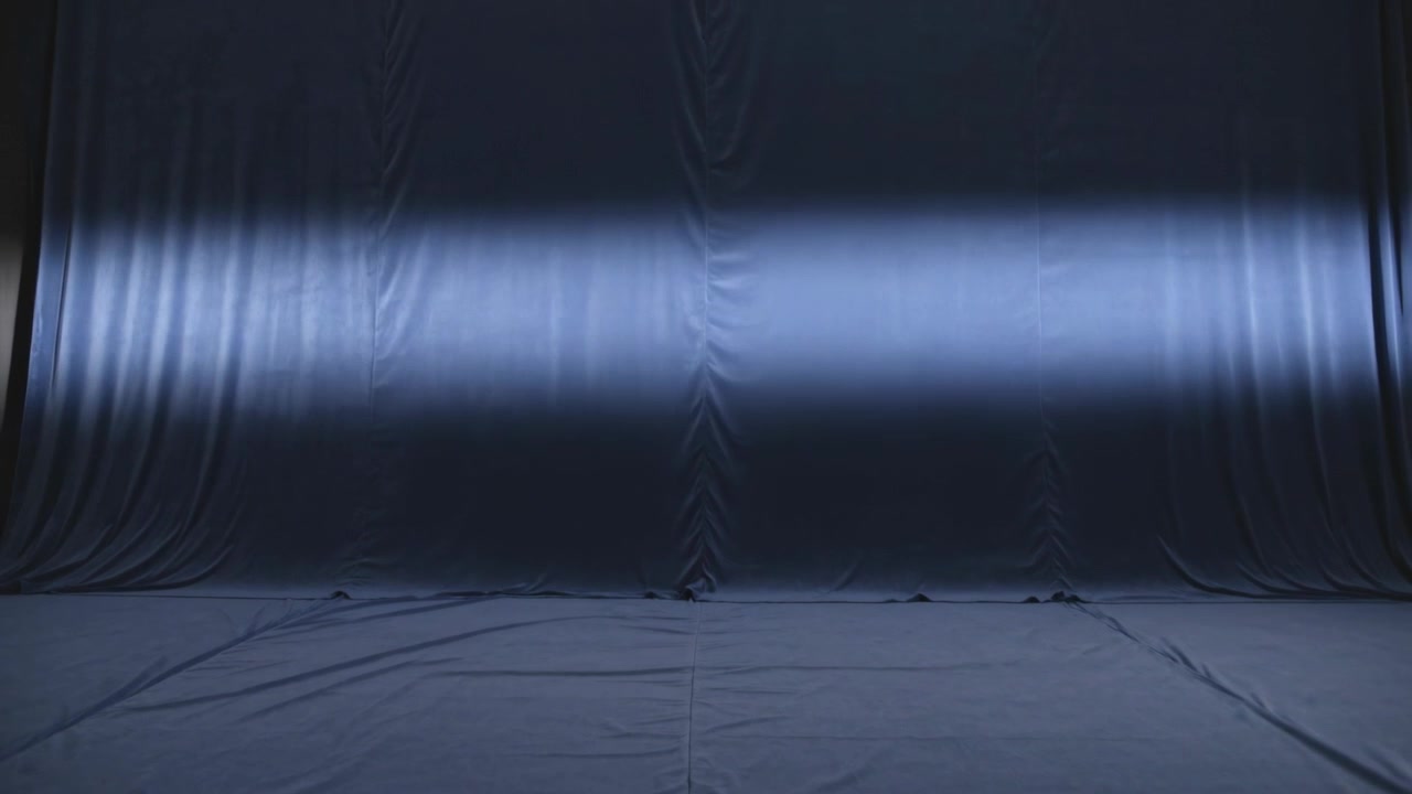 Appearing horizontal spotlight band sweeping upward across studio dark blue curtain, lighting test