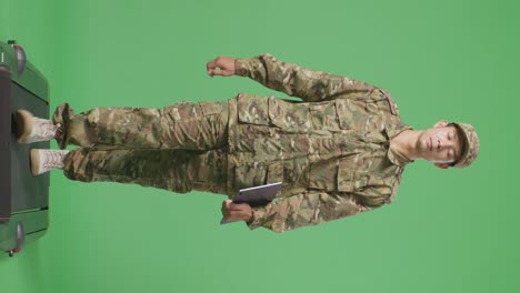 cuerpo lleno de hombre asiático soldado sosteniendo una tableta mientras caminaba en la pantalla verde estudio de fondo