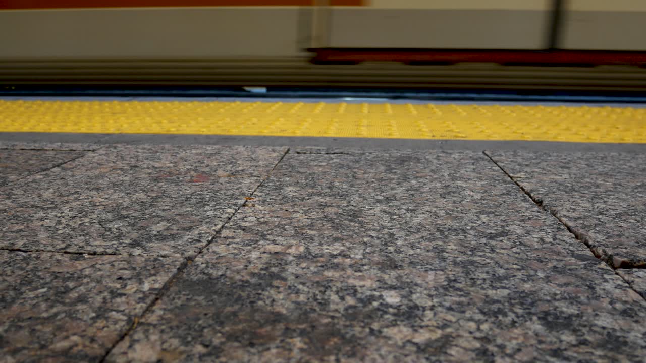 경전철이 역에 정차하고 역 보도를 따라 걷는 많은 사람들의 신발이 보입니다.