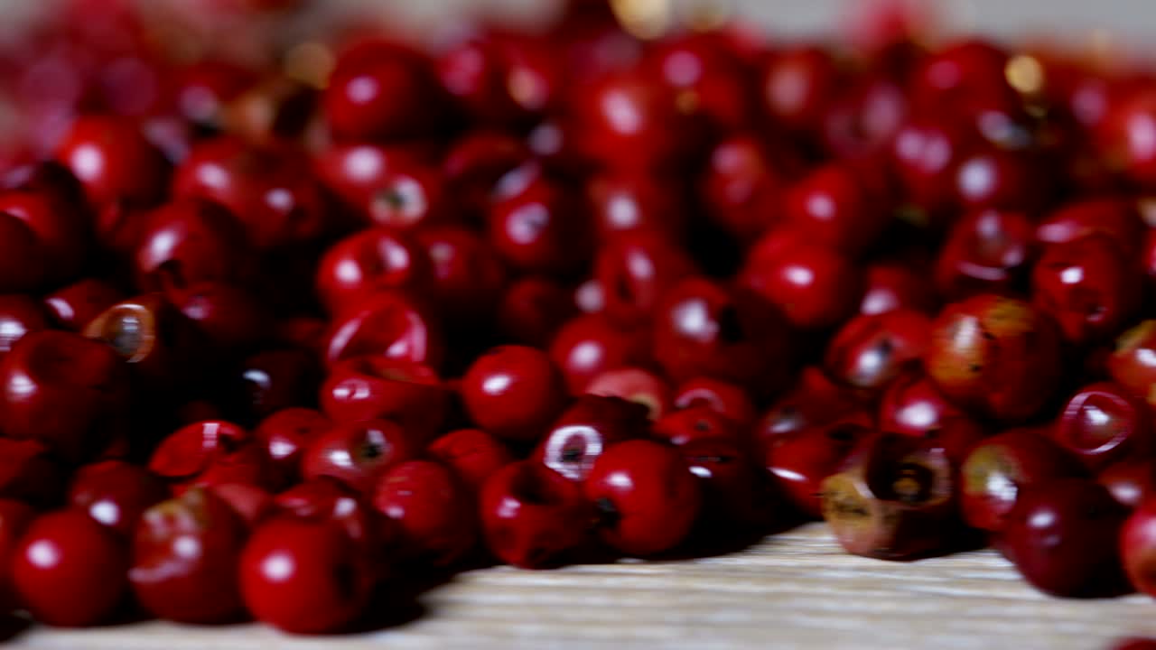 은 고추, 분홍색 고추의 곡물은 극심한 느린 속도로 나무 표면에 떨어지고 서로 여 있습니다.