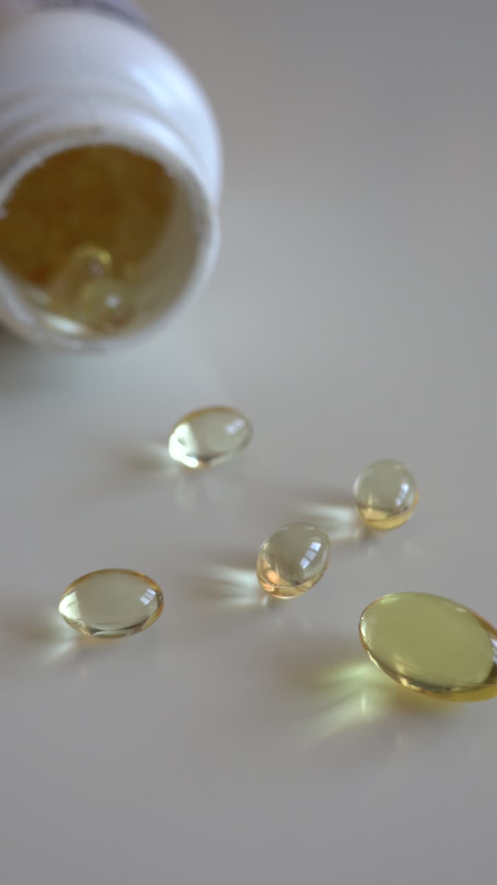 Fish oil omega 3 supplements spilling out of a packer bottle on a white background