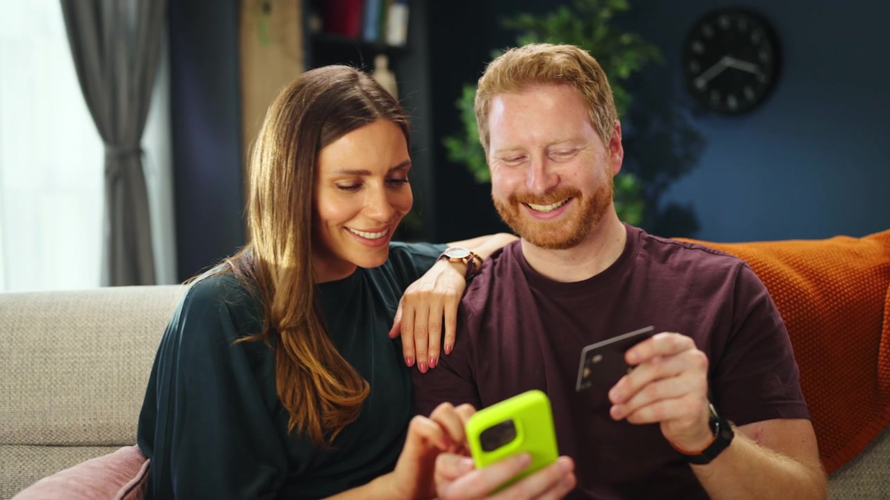 Happy Couple Shopping Online with Smartphone and Credit Card at Home