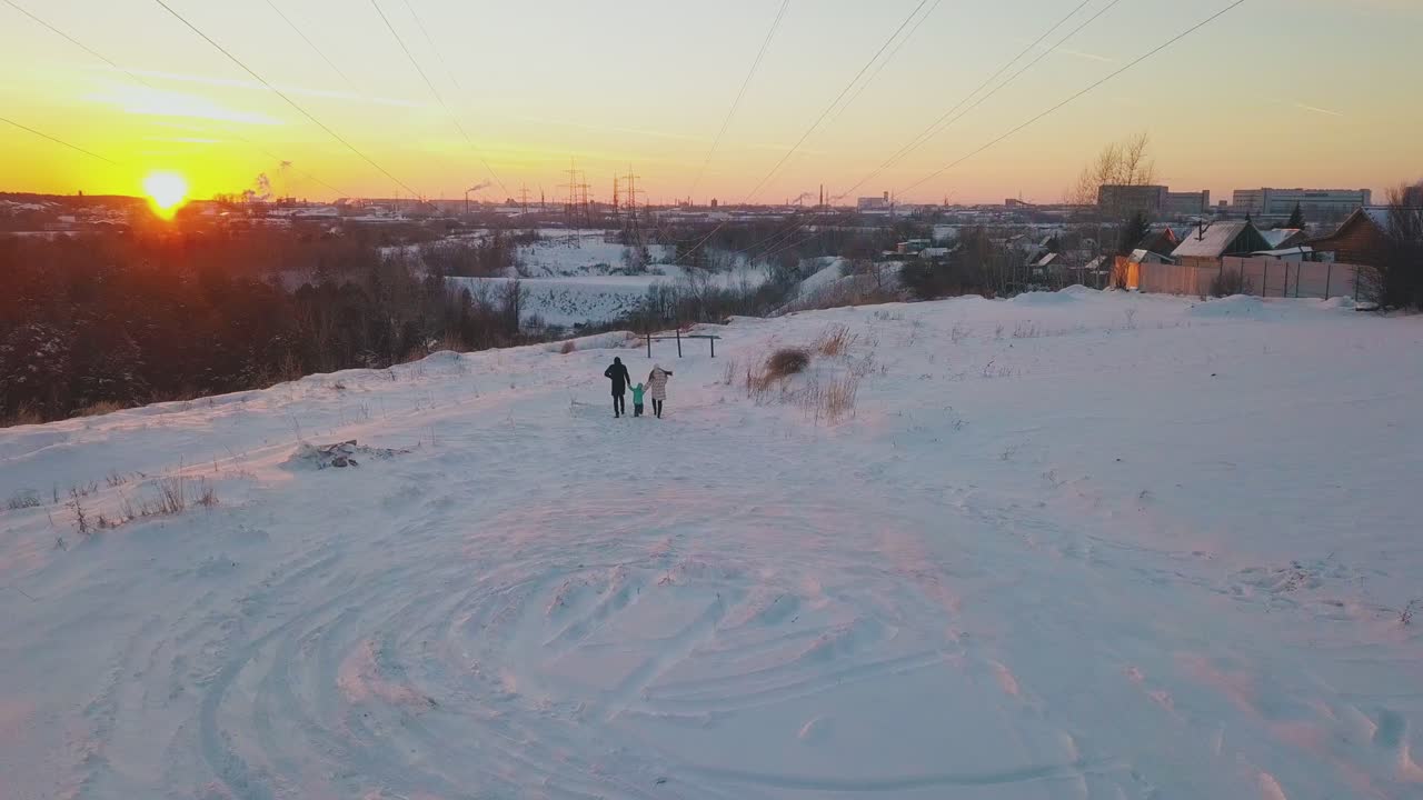 가족 구성원 실루엣이 설원 위 전망을 따라 달리고 있습니다.