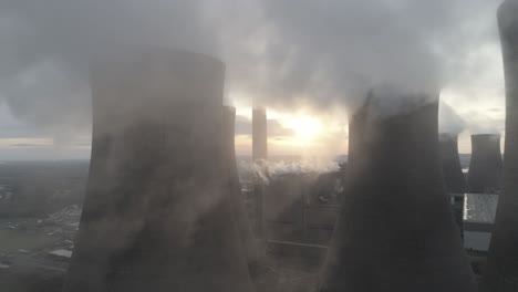 dolly lento aéreo justo al otro lado de la estación de energía torres de enfriamiento humo emisiones de vapor por encima del resplandor del amanecer