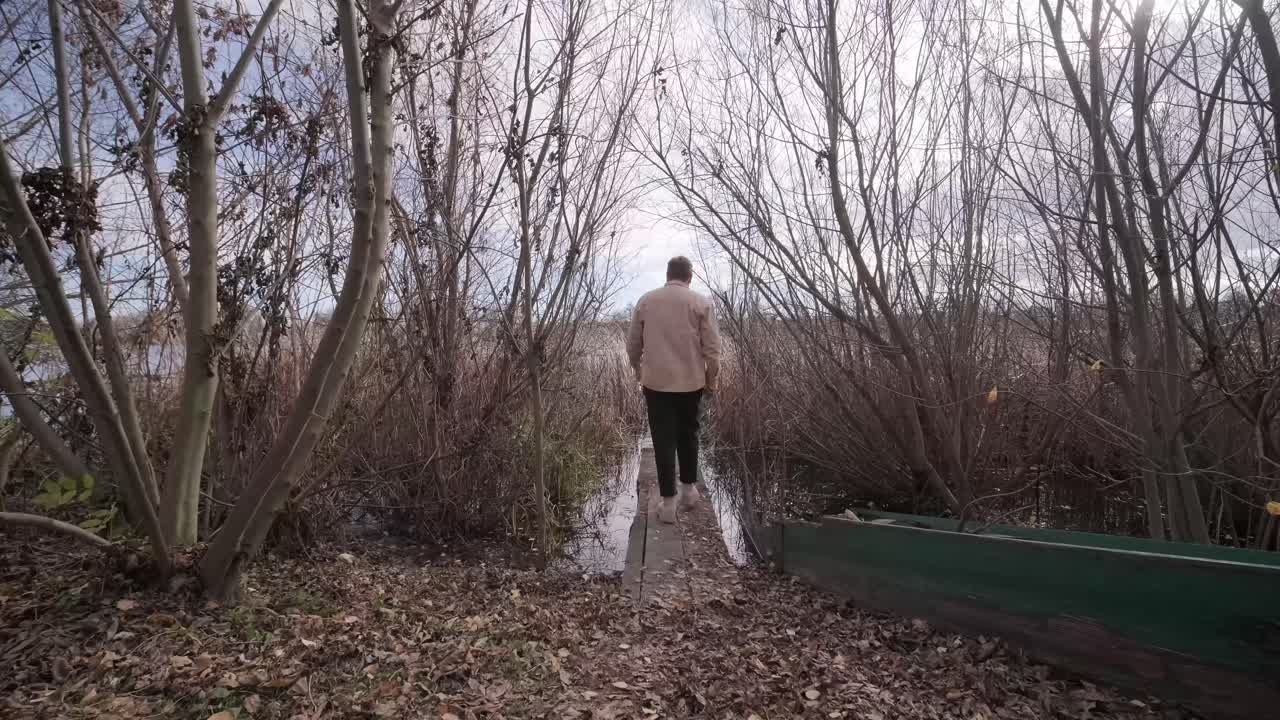 Man walks on wooden pier in a autumn day