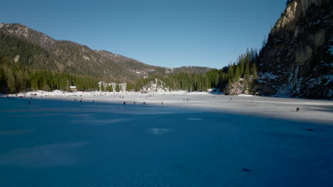 Panoramablick-Auf-Den-Zugefrorenen-Pragser-Wildsee-Mit-Menschen,-Die-Spaß-Beim-Schlittschuhlaufen-Und-Spazierengehen-In-Den-Dolomiten,-Italien-Haben