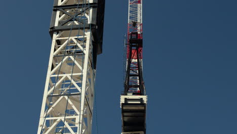 footage of a single construction crane standing still against a clear blue sky. great for videos about construction, engineering, architecture, development, or the built environment.