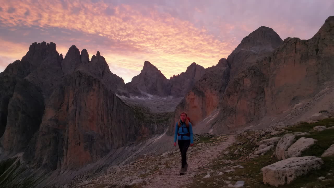 Woman hiking on a mountain trail at sunset or sunrise