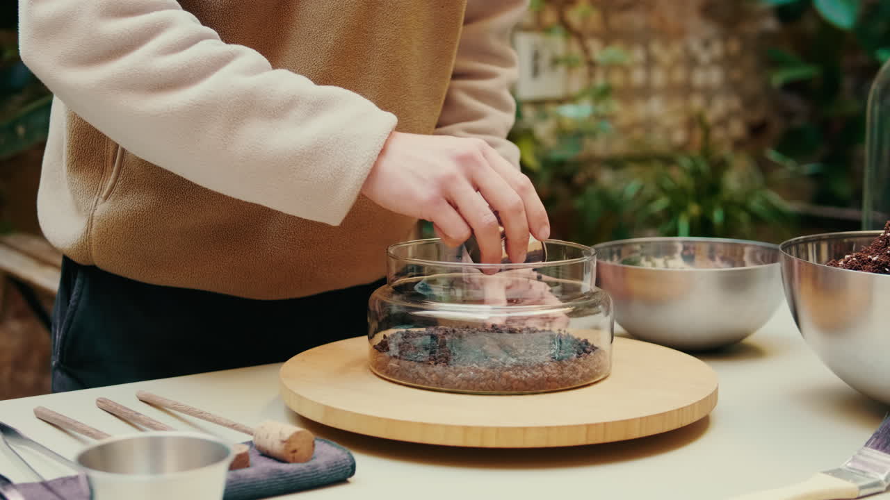 土と砂利を使ってミニチュアテラリウムを作る人の手