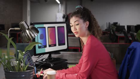 happy biracial female creative using laptop at casual office, in slow motion