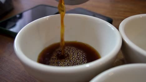 disparo en cámara lenta de café fresco recién servido en taza blanca