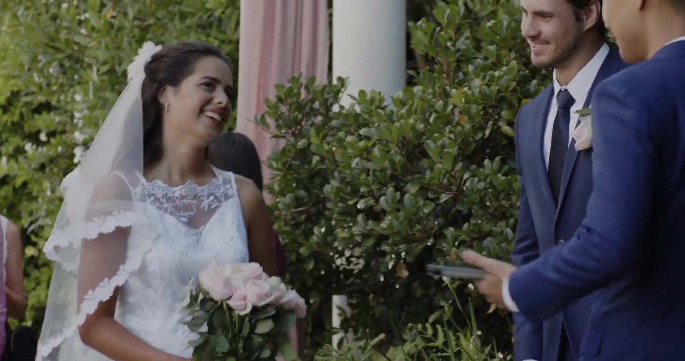L'officiante si protende sollevando il velo sulla sposa durante il matrimonio, rivelando il volto con petali animati