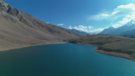 Drone-flying-over-a-bright-blue-mountain-lake-during-autumn-season