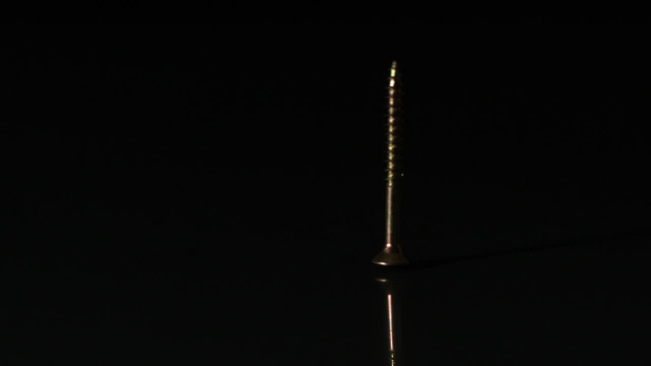 tornillo que cae sobre una superficie negra