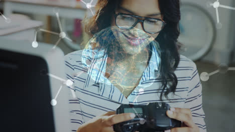 Human-brain-spinning-over-biracial-female-photographer-holding-a-digital-camera-at-office