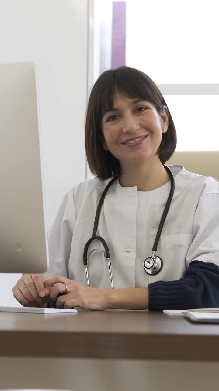 Confident female doctor writing and smiling while sitting in clinic