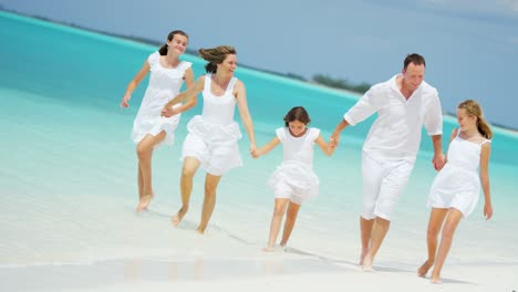 padres caucásicos y sus hijas pequeñas en la playa