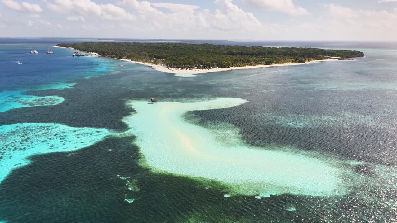 Aerial perspective of Candaraman Sand Bar in Balabac, Palawan, Philippines, featuring turquoise shallows, surrounding coral reefs, and dense forest coastline under a partly cloudy sky