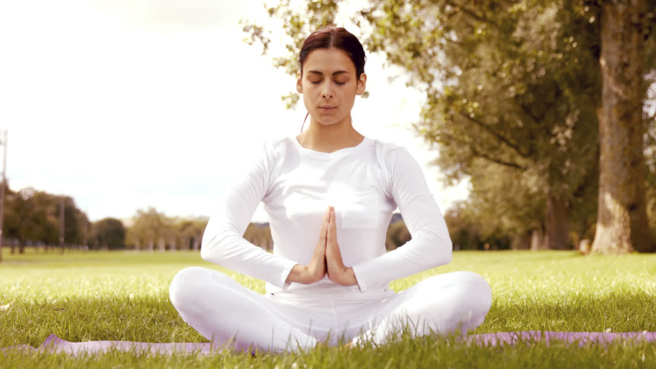 bruneta haciendo yoga en el parque.