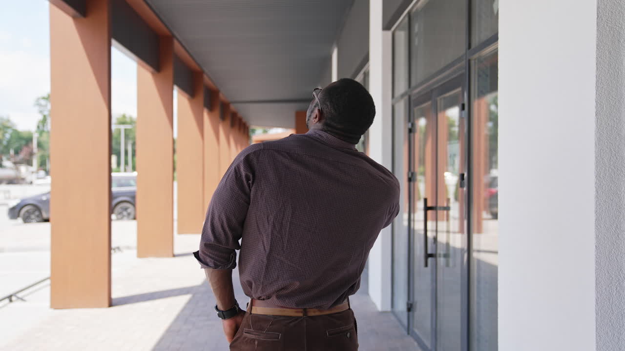 African american man talking the phone outdoors. Back view of unrecognizable man solving business problems through the phone in the city. Rear view.