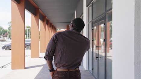 african american man talking the phone outdoors. back view of unrecognizable man solving business problems through the phone in the city. rear view.