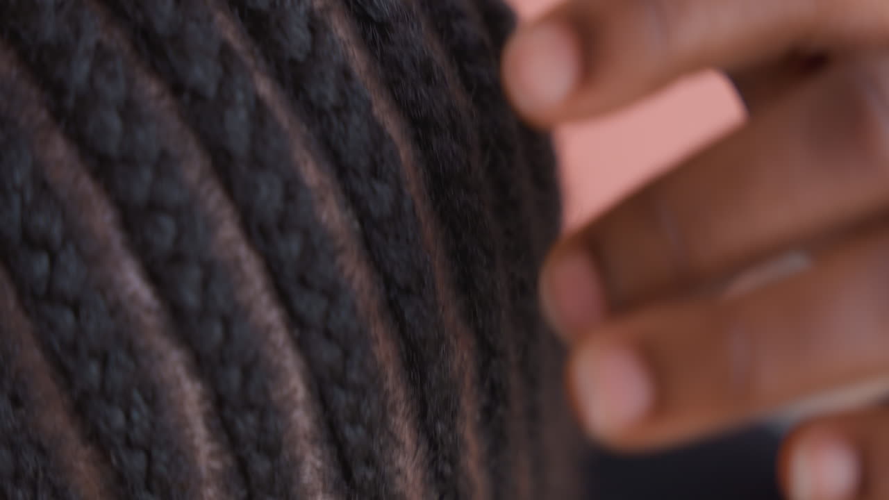 Attenta cura delle trecce. Donna che modella accuratamente le texture dei suoi capelli. Inquadratura focalizzata su cuoio capelluto e aggiustamenti delle trecce. Vista intima che cattura le pratiche culturali di cura dei capelli e i dettagli del cuoio capelluto texturizzato