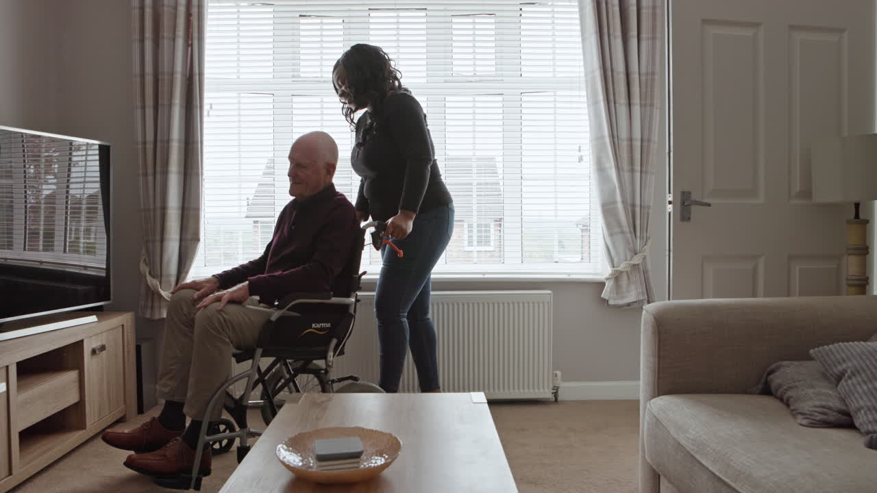 Elderly man in wheelchair with caregiver at home