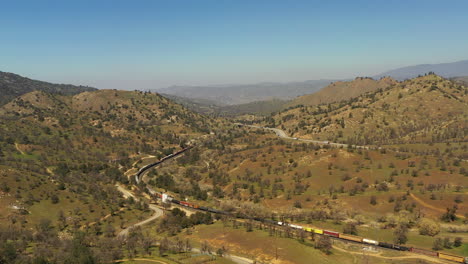 a long union pacific train traveling along the tehachapi tracks - aerial view slow motion