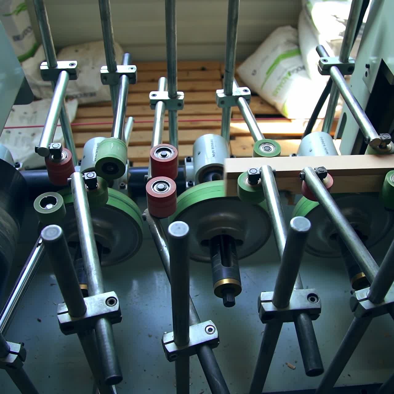 Equipment with numerous rotating rollers. Metal beams moving quickly by the machine. Top view