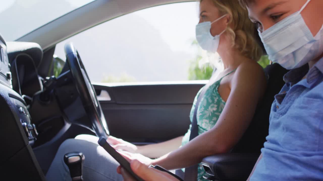 madre y hijo caucasianos sentados en el coche, con máscaras faciales