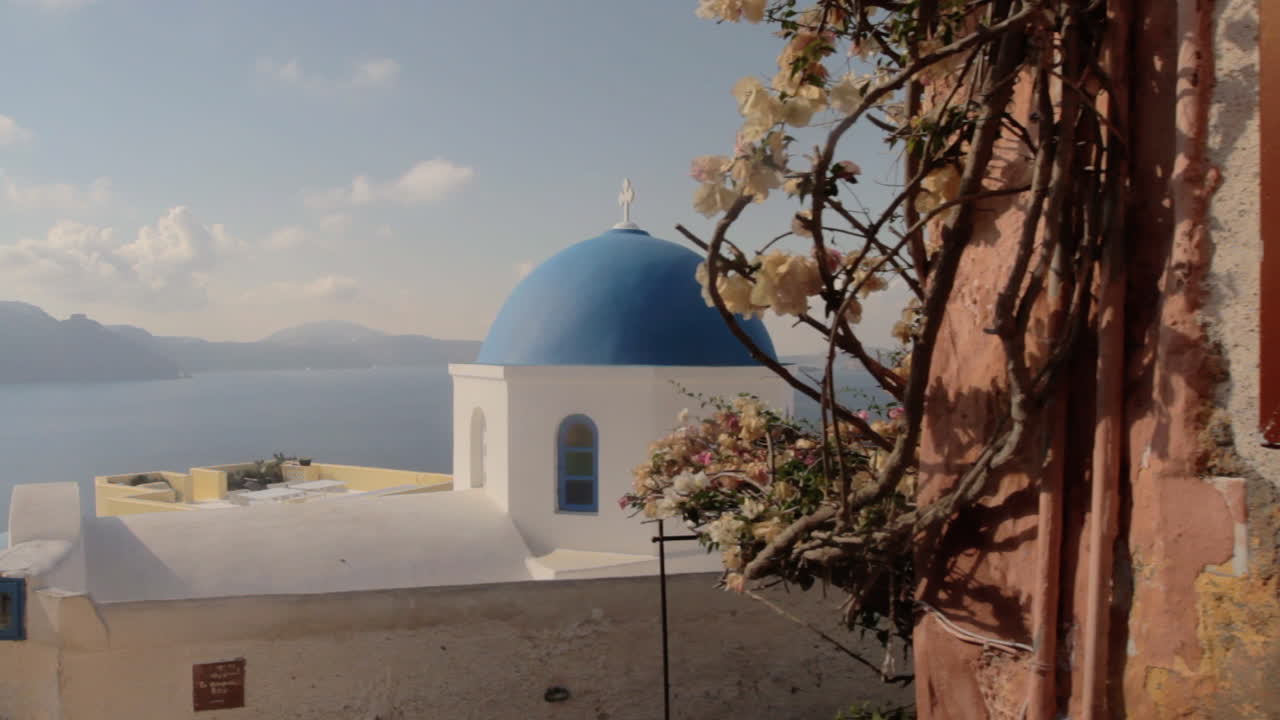 una pequeña capilla ortodoxa griega con una cúpula azul con vistas al paisaje marino de santorini