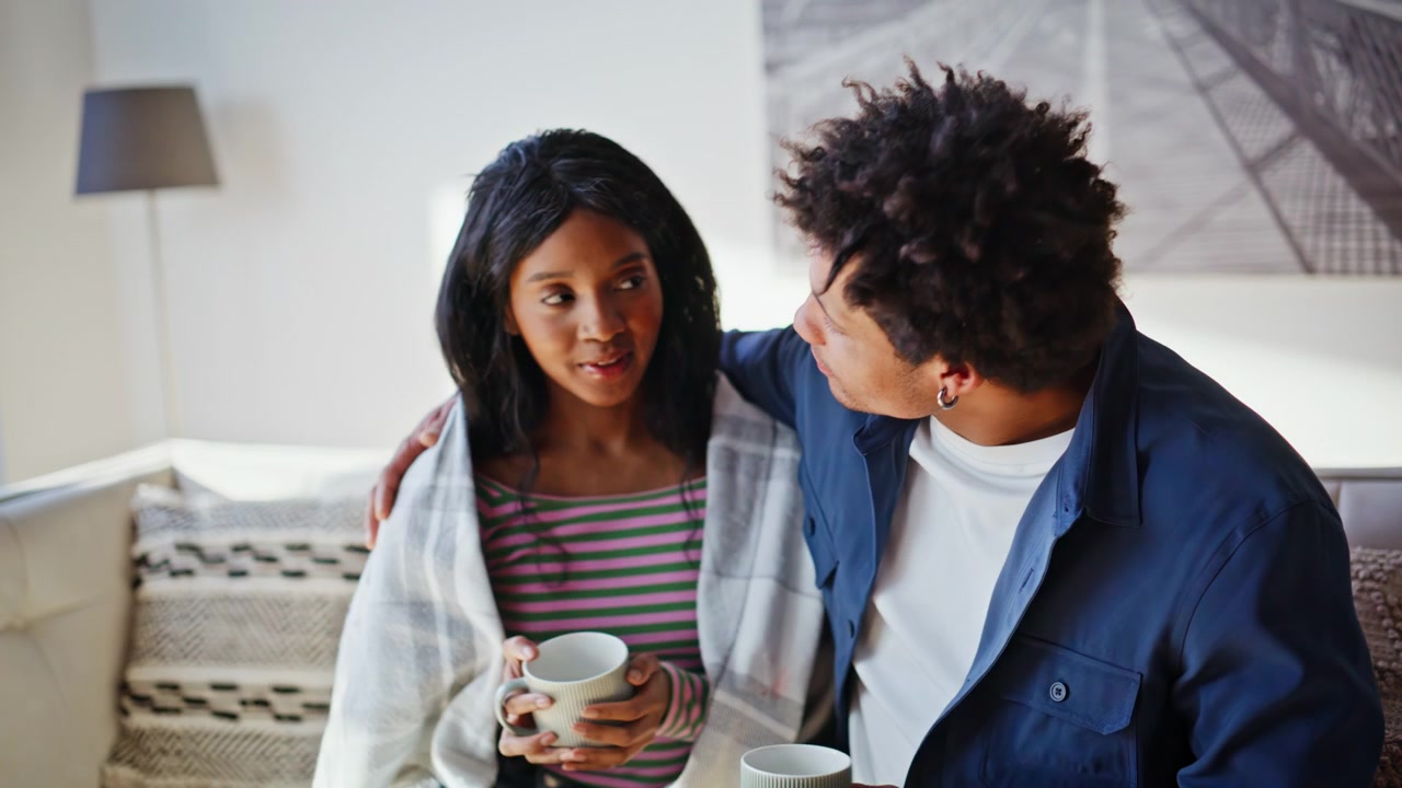 Happy couple drinking coffee together on sofa cozy room peaceful morning closeup