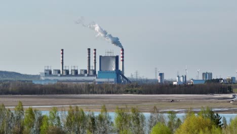 Aerial-panoramic-of-power-plant-station-with-smog-co2-air-pollution-from-chimney-surround-by-green-natural-land-and-river