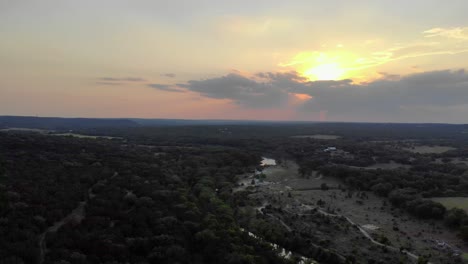 Aerial-flying-right---then-pulling-back-over-fields,-trees,---river-at-sunset