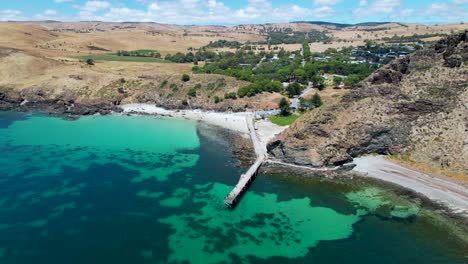 un drone de 4k volando hacia atrás para revelar un largo muelle que sobresale en un océano azul brillante