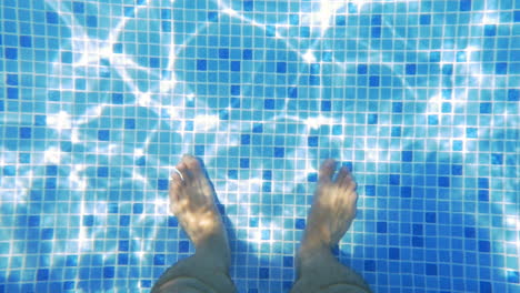 man feet in sunlit swimming pool