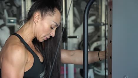 a beautiful strong woman trains the muscles of her arms and back. strength training in the gym
