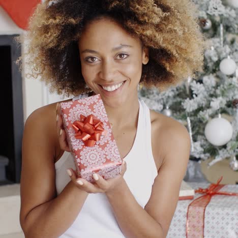 Pretty-smiling-woman-displaying-a-Christmas-gift